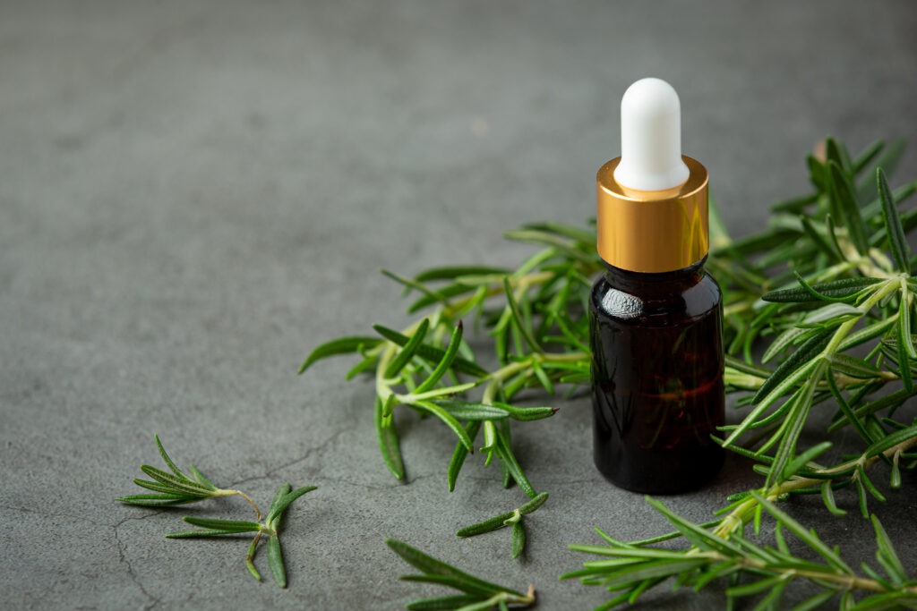 Dark glass dropper bottle with rosemary leaves, debunking popular hair care myths naturally.
